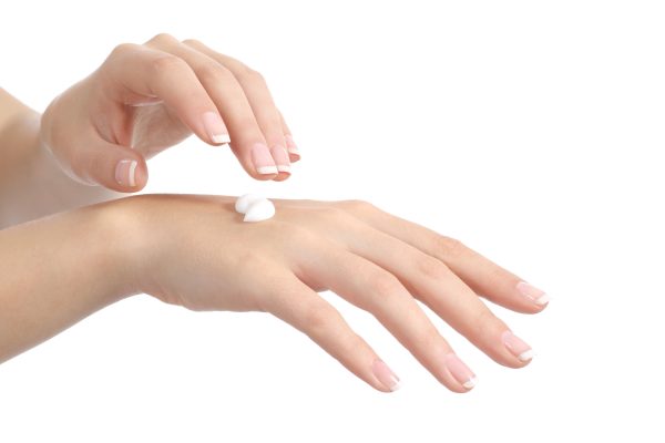 Woman hands with perfect manicure applying moisturizer cream isolated on a white background