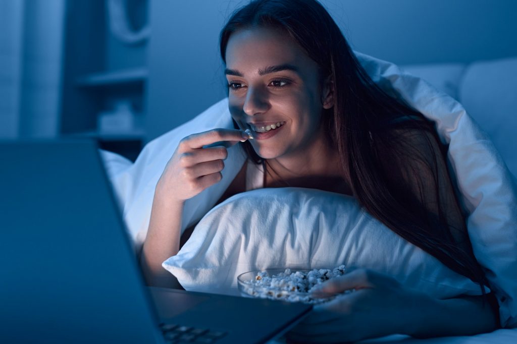 Cheerful female watching film at night