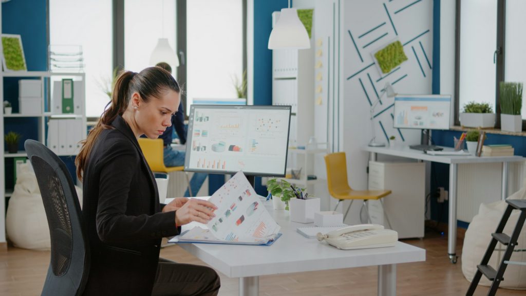 Businesswoman working with computer and data charts on paper