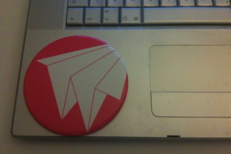 Close up of a laptop keyboard and trackpad with a large pink circular badge with the white Wunderbar logo on it. The logo looks like a paper airplane in the shape of a letter W.
