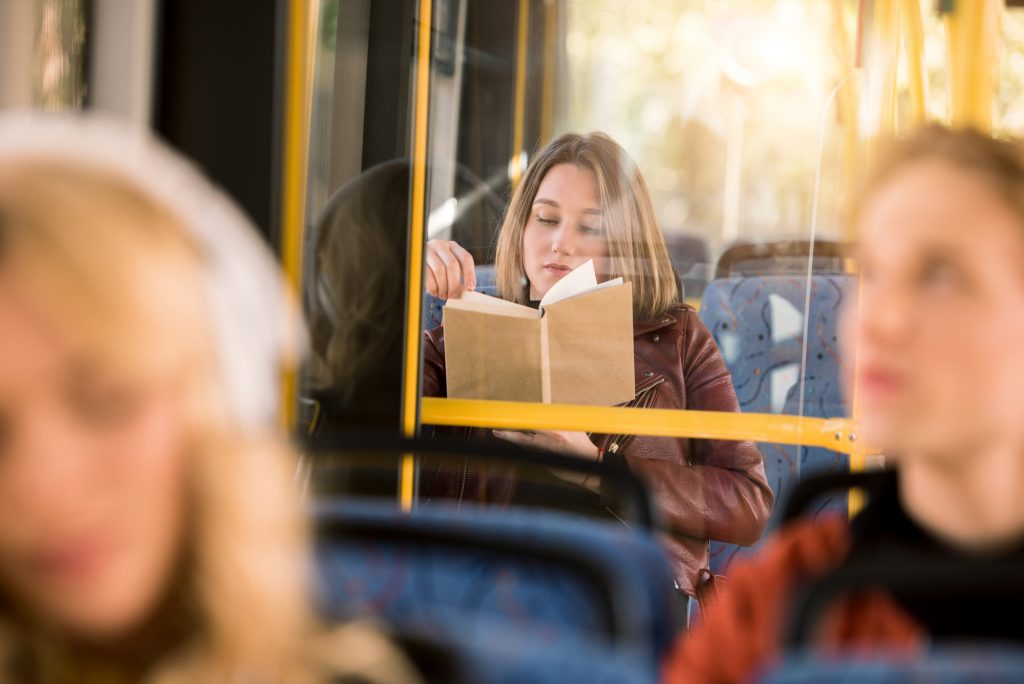 Kvinde læser en bog i bussen