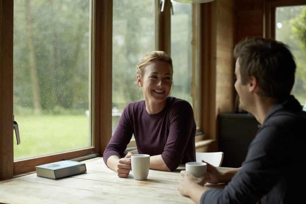 Kvinne og mann samtaler over en kopp kaffe.