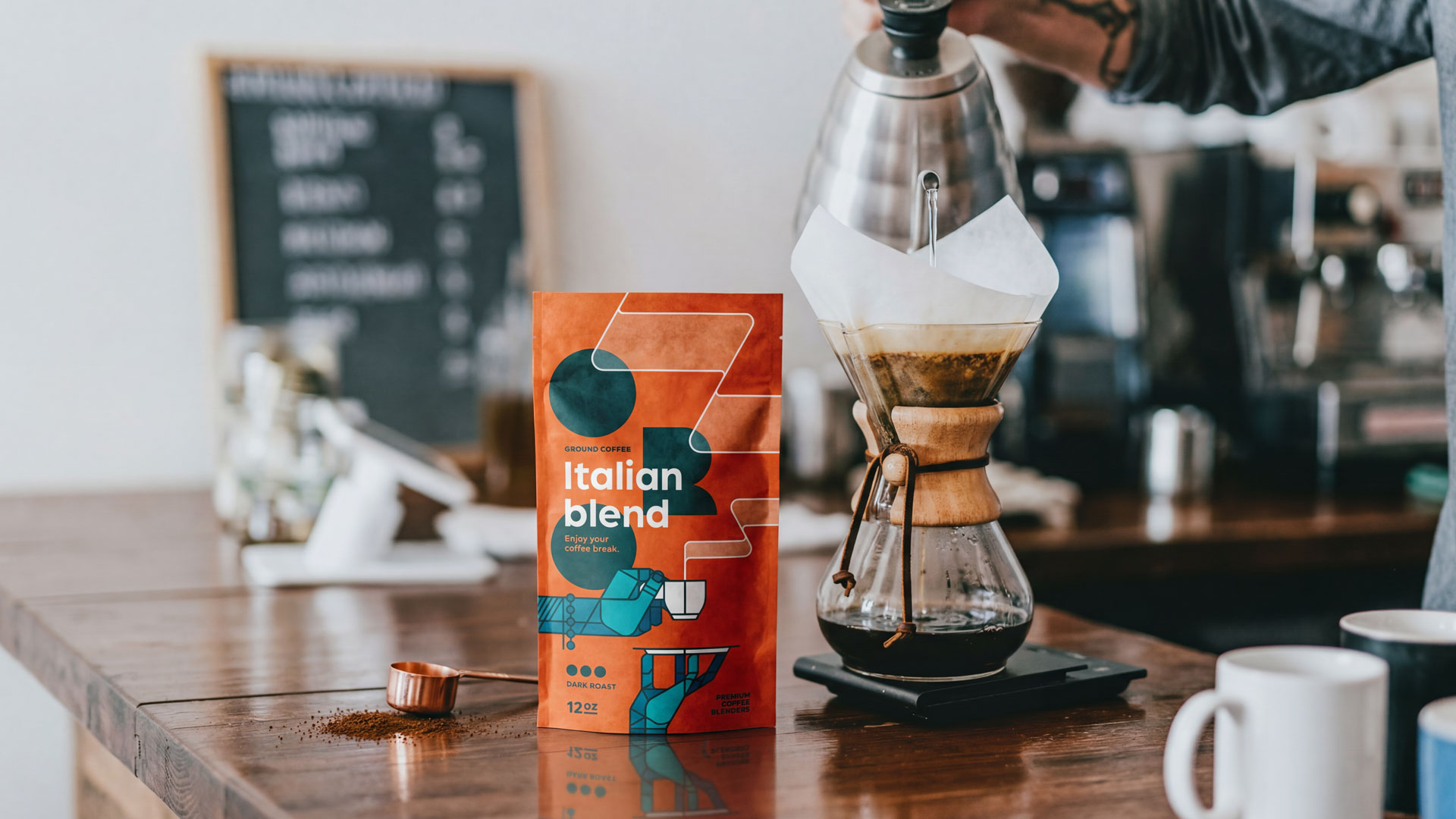 ORO Italian Blend coffee packaging displayed in a modern café environment beside a pour-over brewing setup. Packaging design by Bart De Keyzer featuring bold typography, geometric illustration, and vibrant editorial-inspired branding for a contemporary coffee brand.