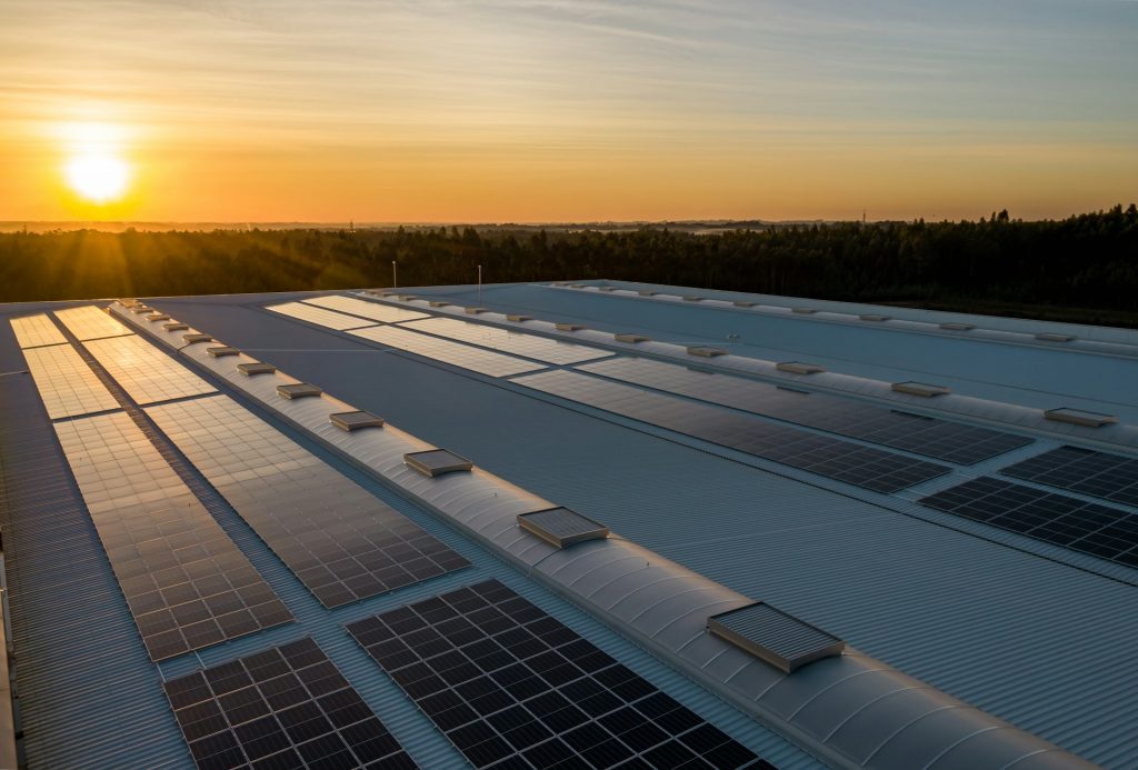 Solcellspaneler på ett tag i solnedgång med natur runtom omkring