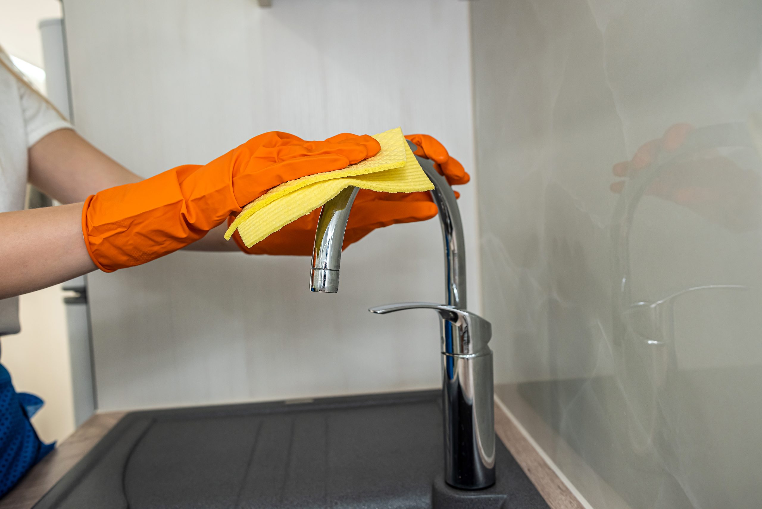 closeup view, female hand wearing rubber protective gloves and clean kitchen. all for professional disinfection at home