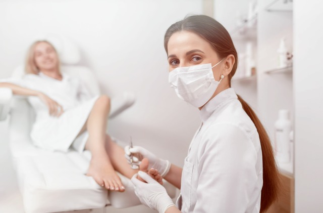 Podiatrist in mask on face looking at camera and working.
