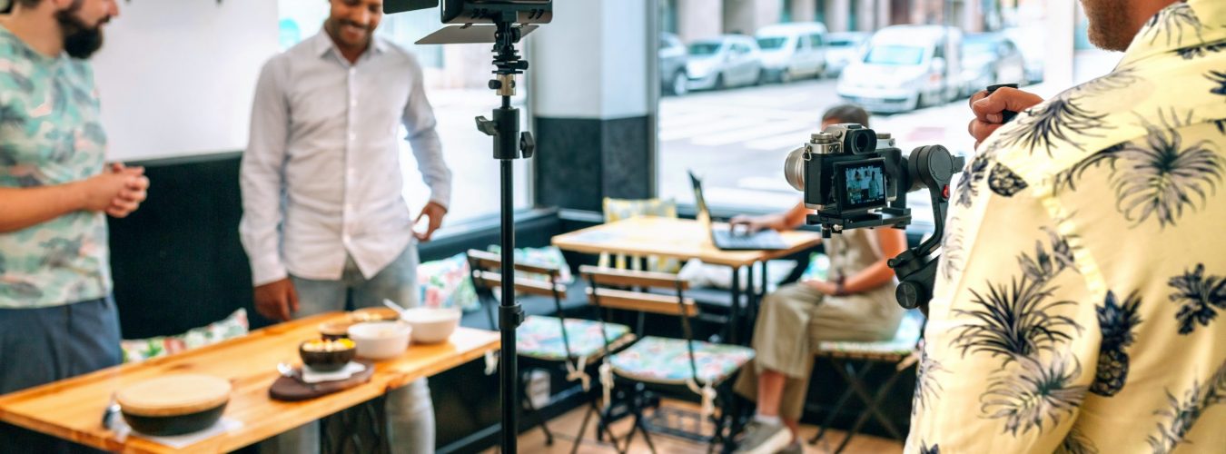 Cameraman recording a cooking tutorial that is broadcast live. Selective focus on camera in foreground