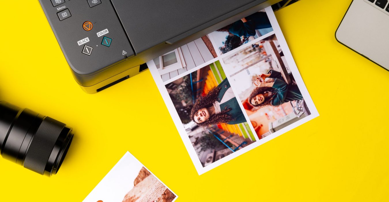 Printer printing colorful photos of people close up, yellow background, studio shot