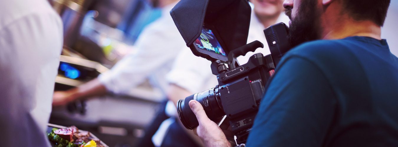 videographer recording while Professional team cooks and chefs preparing meal at busy hotel or restaurant kitchen