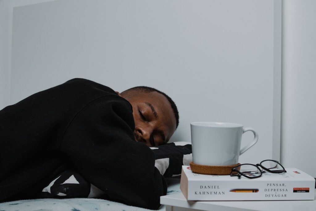 a man sleeping on a bed next to a stack of books