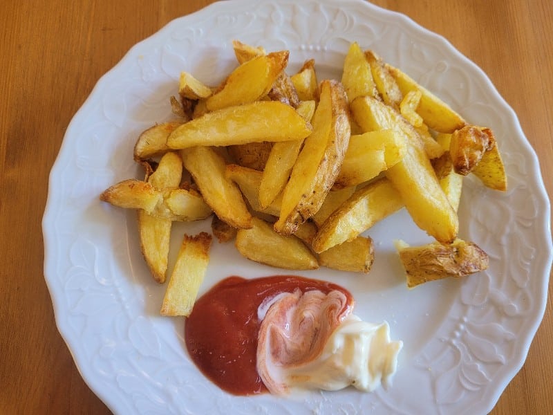 Ein Teller voll mit dicken Pommes und einem KLecks Ketchup und Mayo