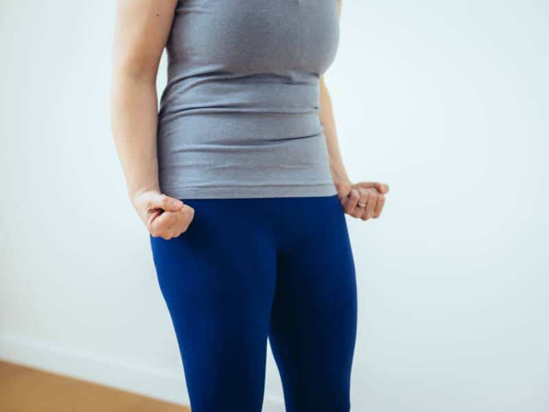 Man sieht den Mittelteil eines Frauenkörpers in Sportkleideung. Sie hat den Bauch sichtbar angespannt und gefestigt.