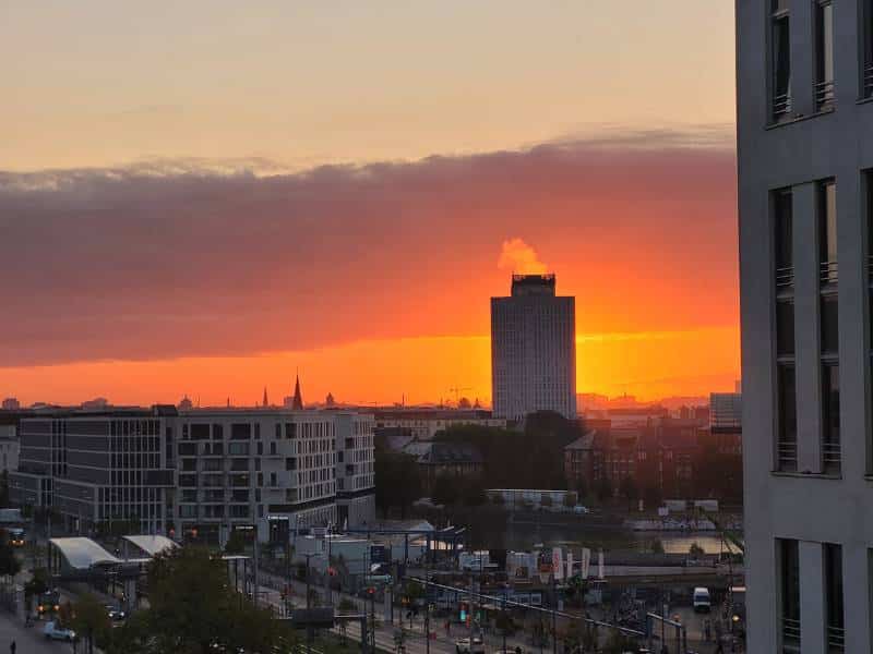 Blick aus dem Hotelfenster im 7. Stock eines Hotels. Es ist gerade Sonnenaufgang und der Himmel ist enstprechend rotglühend.