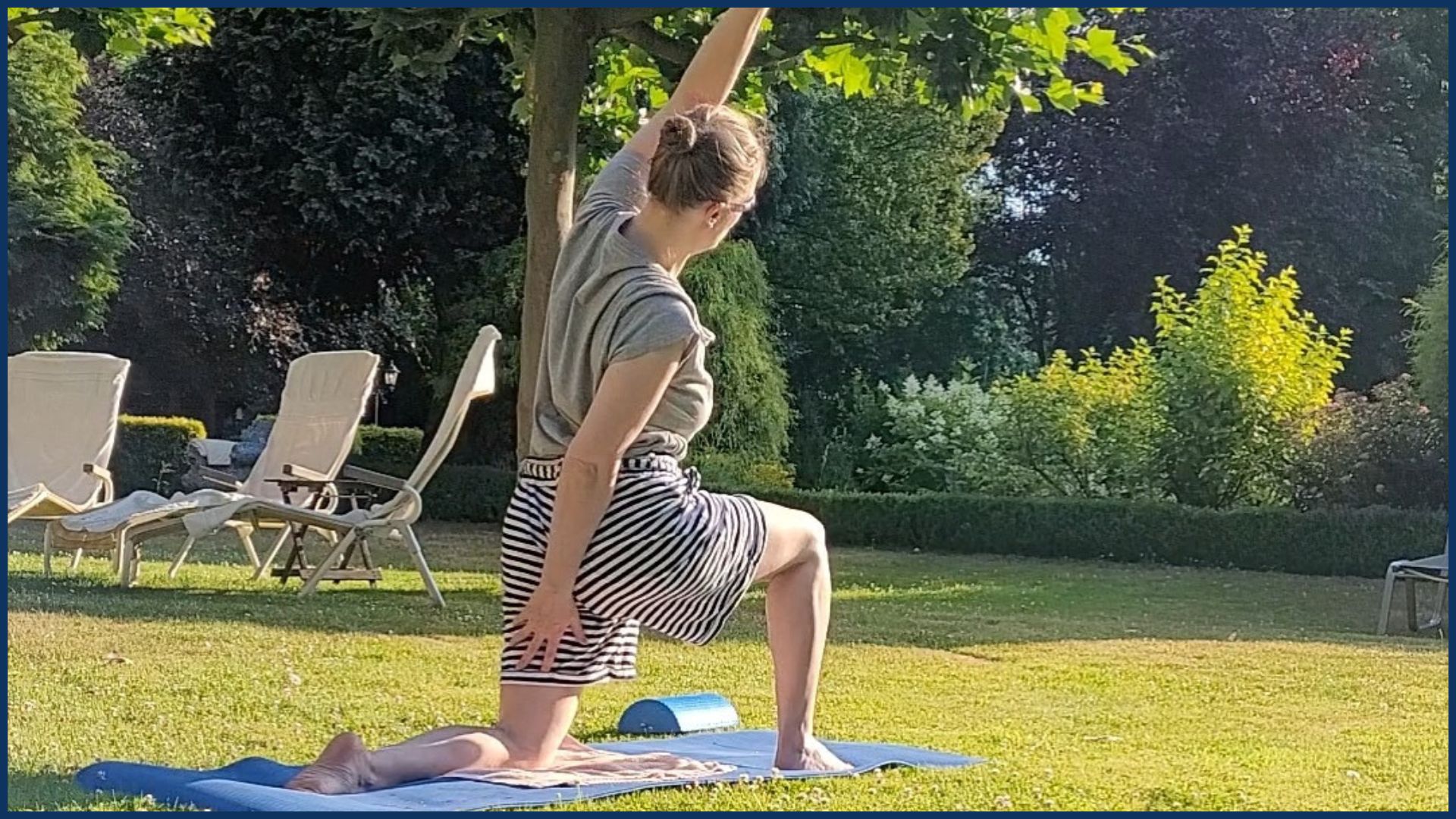 Man sieht eine Frau auf einer Yogamatte, die auf einer Wiese eine Übung macht. Es ist sonnig.