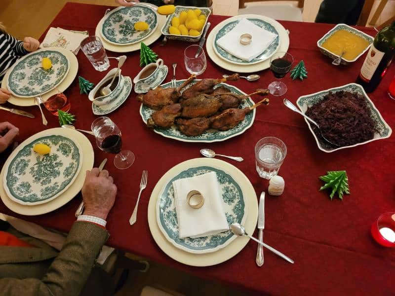 Ein festlich gedeckter Tisch mit Gans, Rotkohl und Kartoffeln.