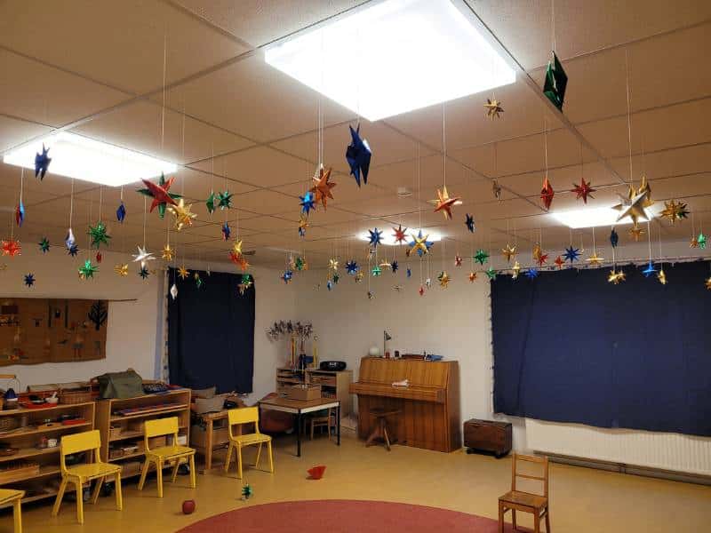 Blick in einen Kindergartenraum, an dessen Decke ungefähr vier Dutzend selbstgebastelte Sterne hängen.