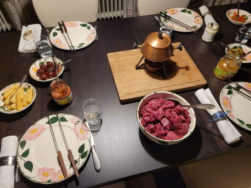 Blick auf einen gedeckten Tisch mit Fondue-Topf und entsprechenden Zutaten.