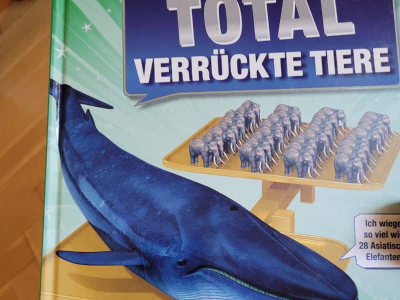 Ein Buch: Total verrückte Tiere. Das Titelbild zeigt eine Waage, auf der vorne ein Blauwal ist und hinten viele Elefanten. Eine Sprechblase bei dem Wal sagt: Ich wiege so viel wie 28 Asiatische Elefanten.