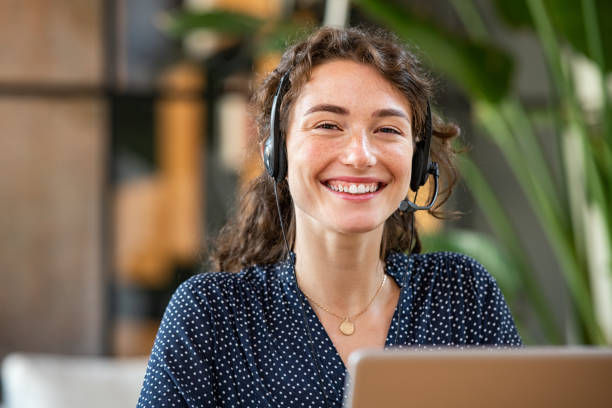 Leende kvinna som tittar in i kameran, på huvudet ett headset.