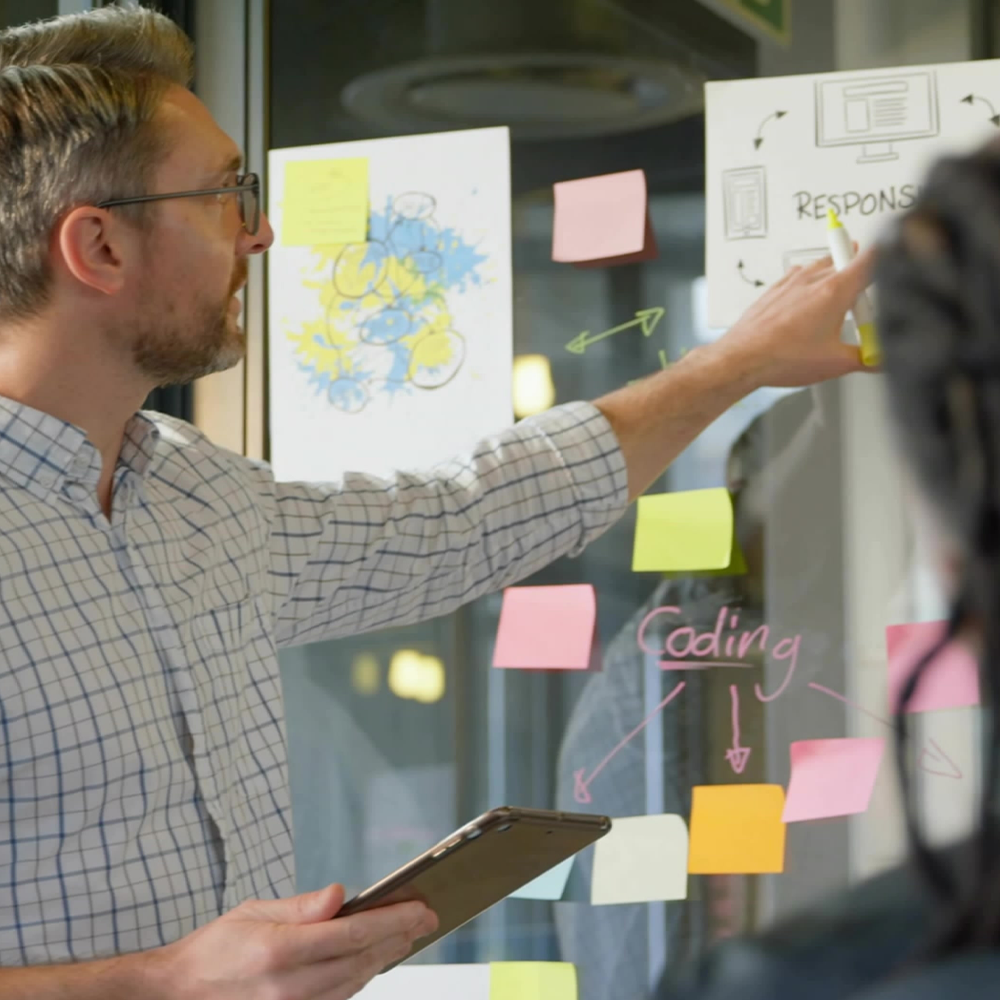 mand peger på tavle med post-its