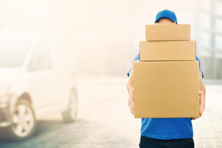 delivery man holding pile of cardboard boxes in front. copy space