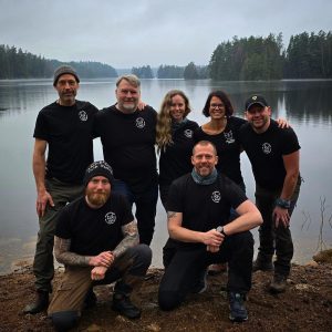 Sju personer i Team All in Nature Sweden står uppställda intill varandra vid en sjö.