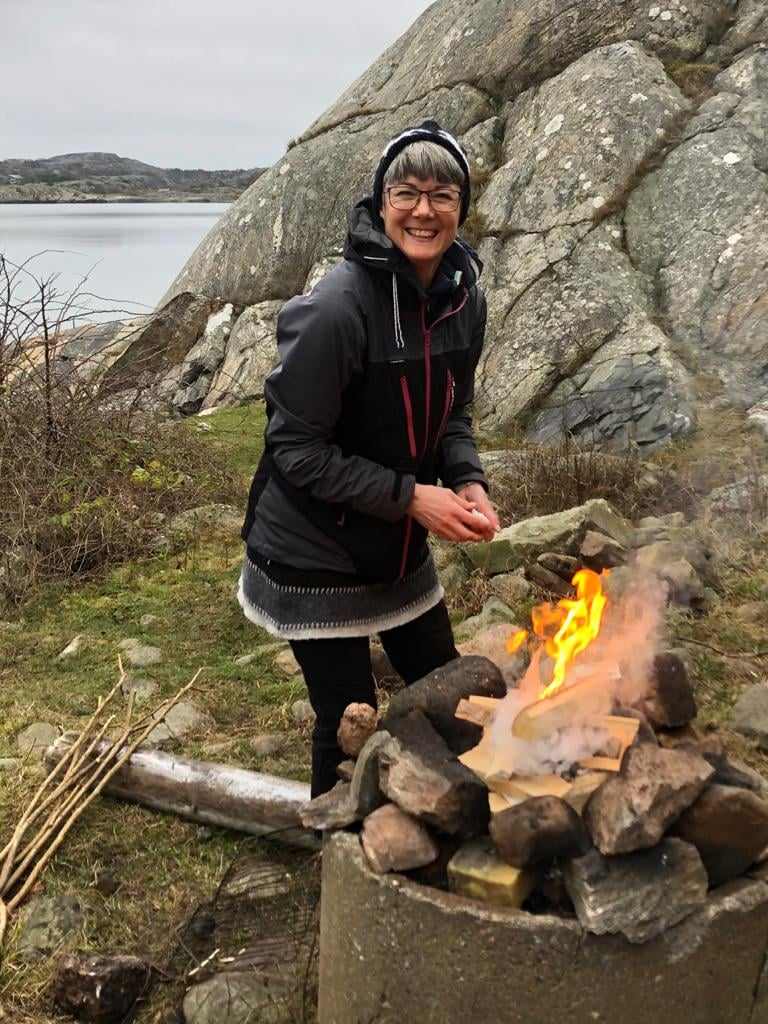 Glad kvinna som eldar i ett betongrör vid havet.