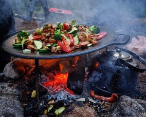 Färgglad mat steks på en muusikka över öppen eld under en matlagningskurs.