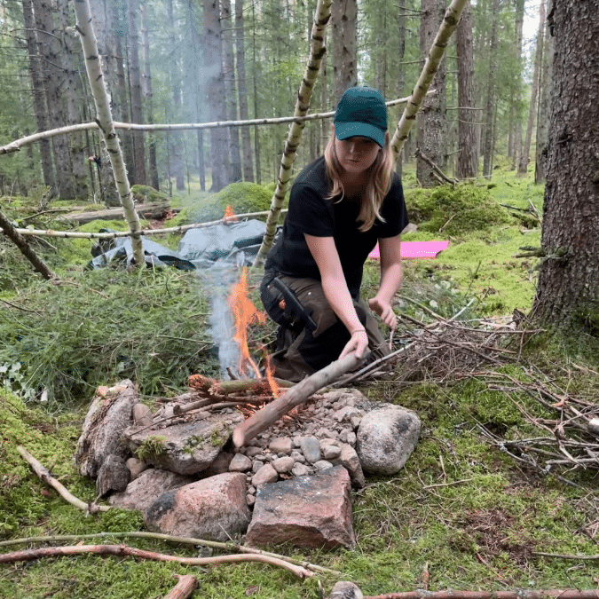 Tjej som eldar på en överlevnadskurs