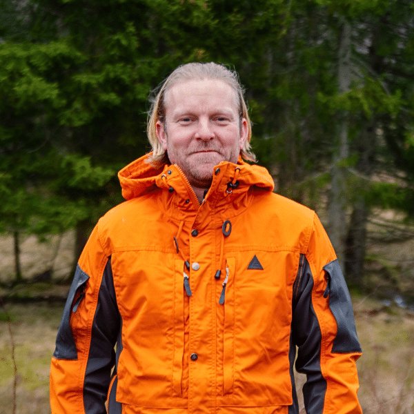 Porträttbild på blond man i orange jacka.