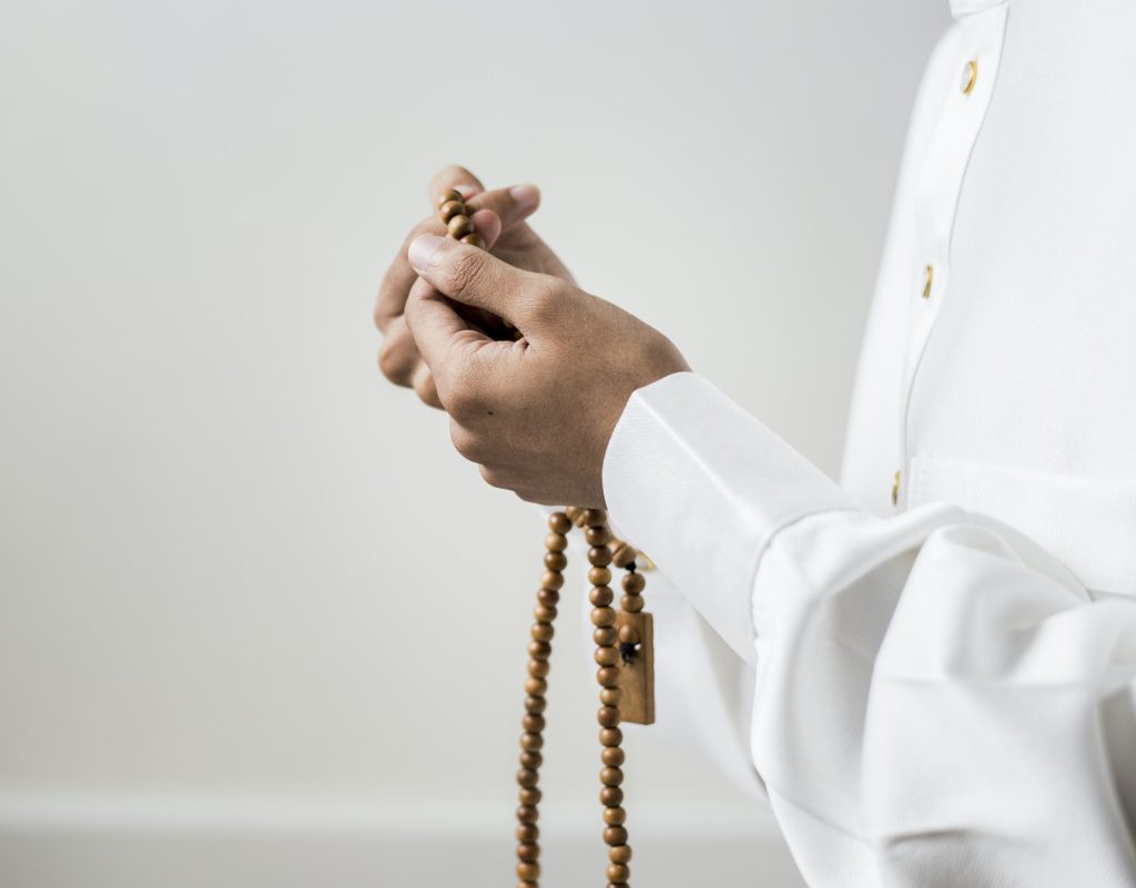 Muslim man using misbaha to keep track of counting in tasbih