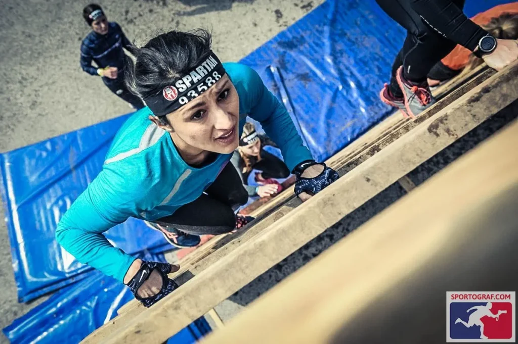 Amanda is climbing an obstacle wall at the spartan race