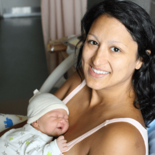 A newly postpartum mother holds her hours old baby in her arms