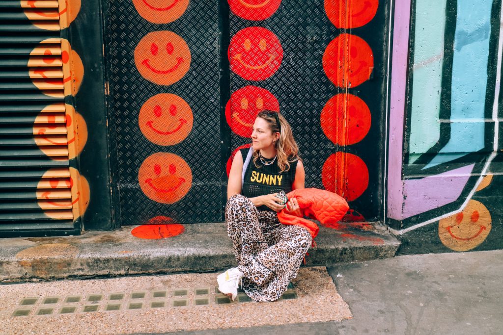 Amber in front of smiley graffiti wall in Shoreditch, London, United Kingdom