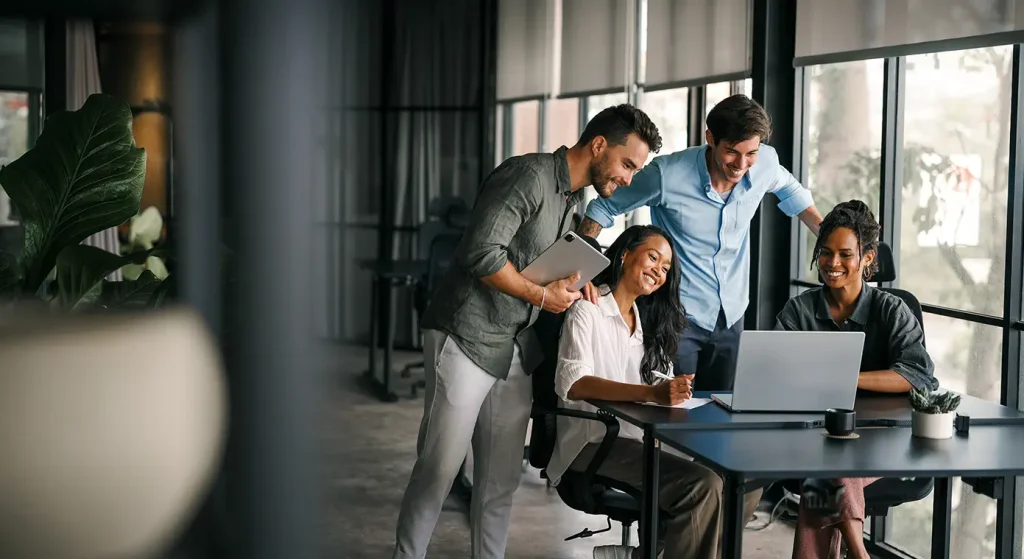 Group of young professionals happily looking at a laptop