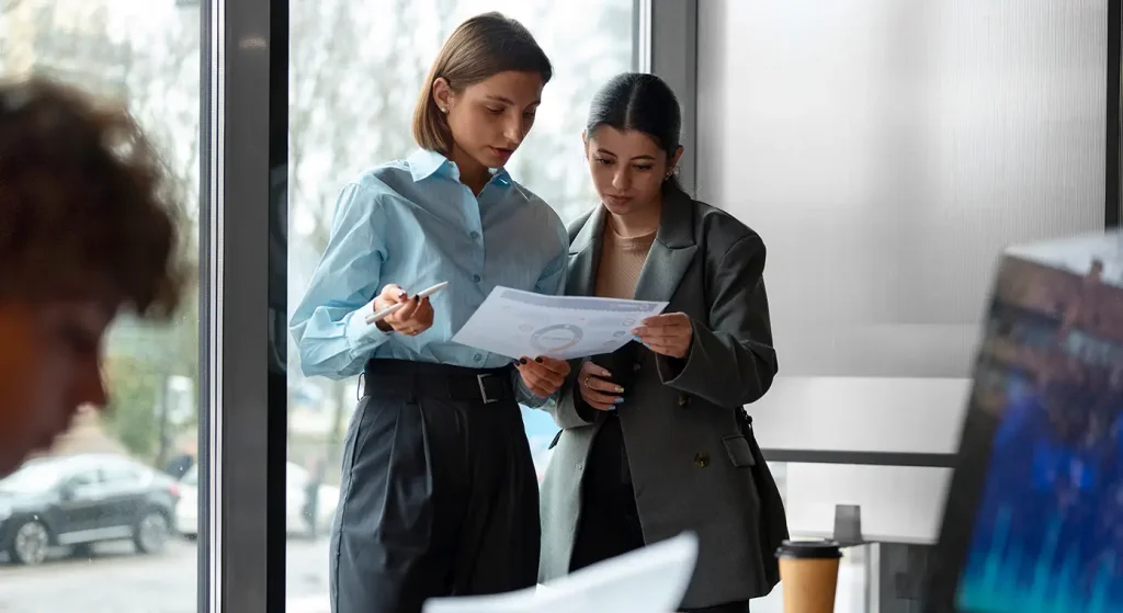Two finance professionals discussing over data on a paper
