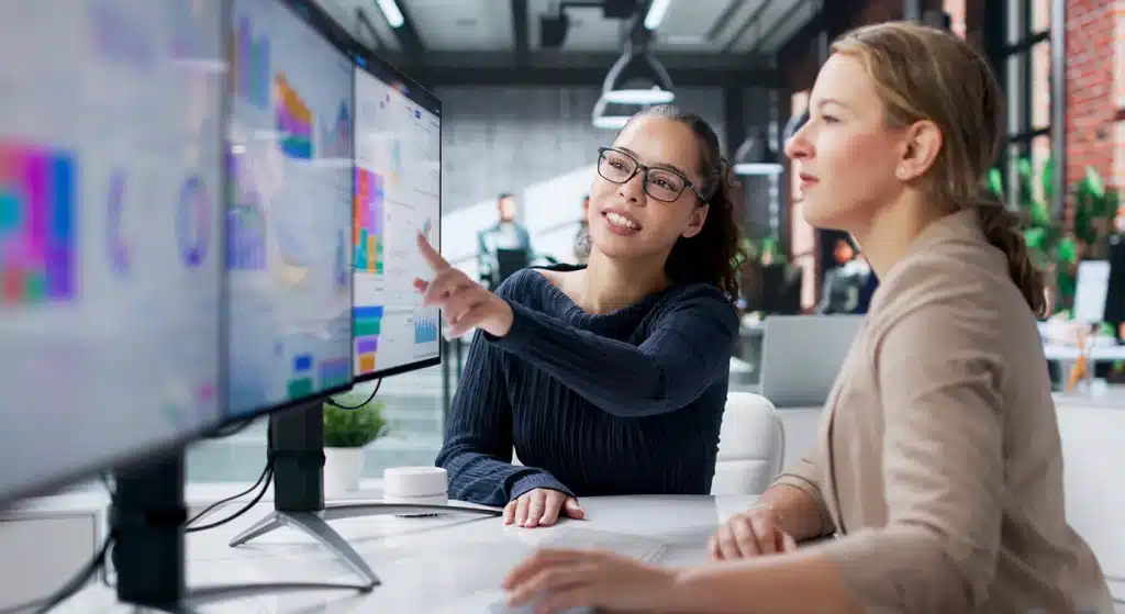 Two finance professionals discussing data on a computer screen