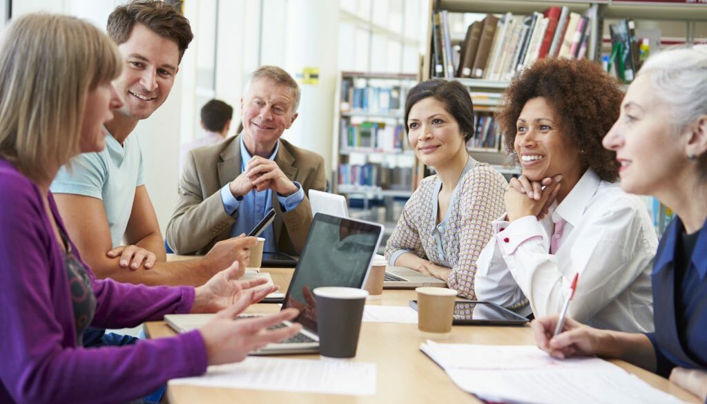 group of mature students collaborating on project in library