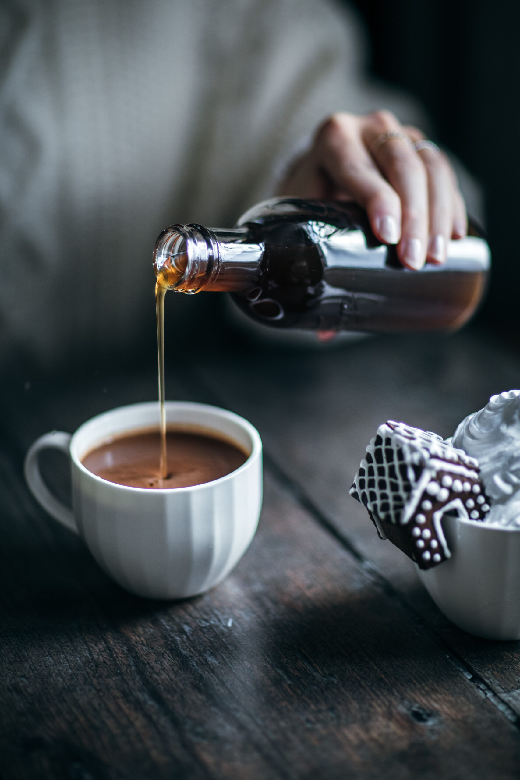 Pouring syrup in a mug with hot chocolate