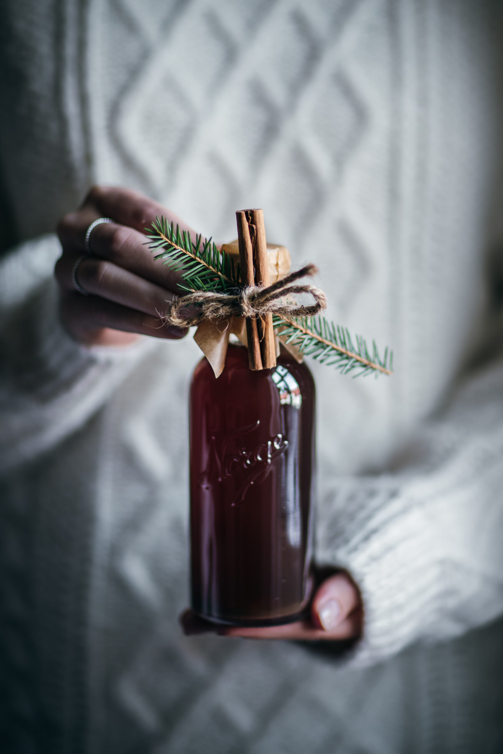 Holding a glass bottle with gingerbread syrup. Decorated with a cinnamon stick.
