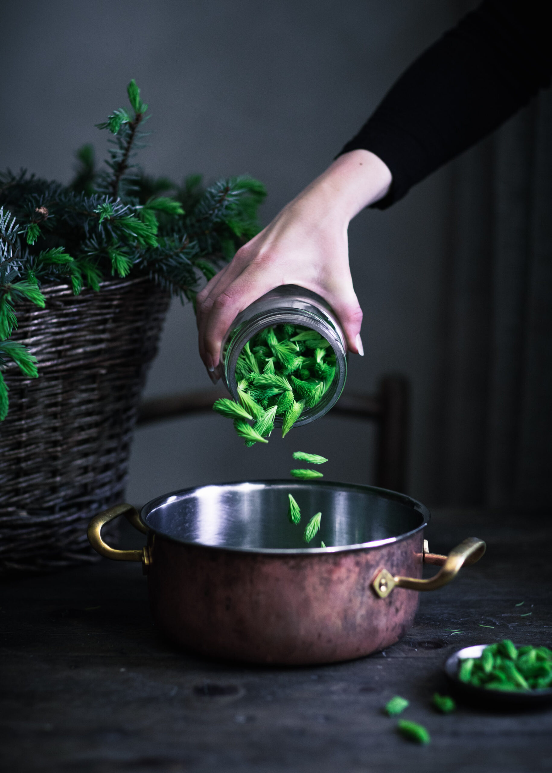 Throwing spruce tips in a copper pan for making spruce tip syrup