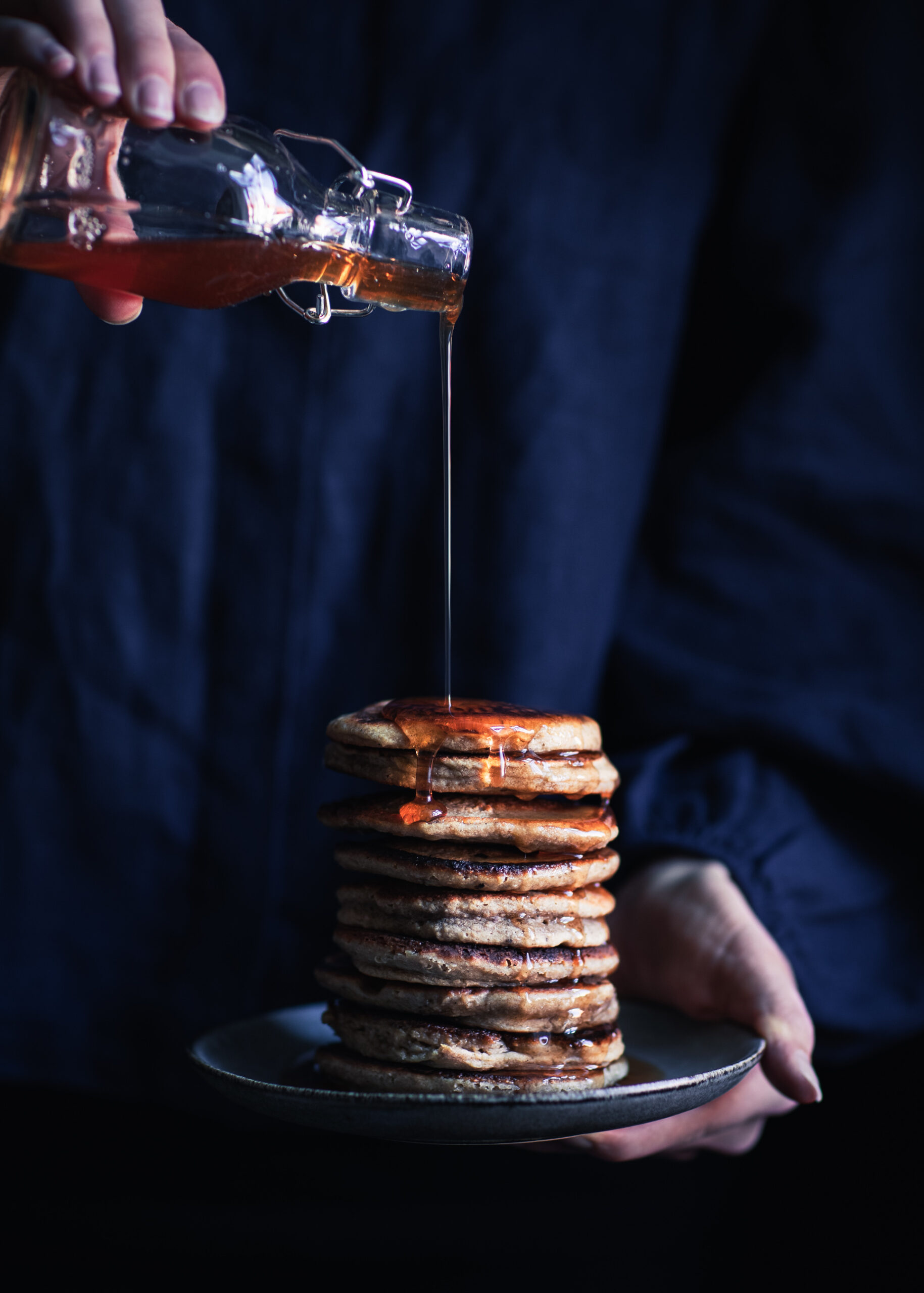 Drizzling homemade spruce tip syrup on pancakes