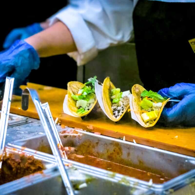 person about to put sauce on tacos