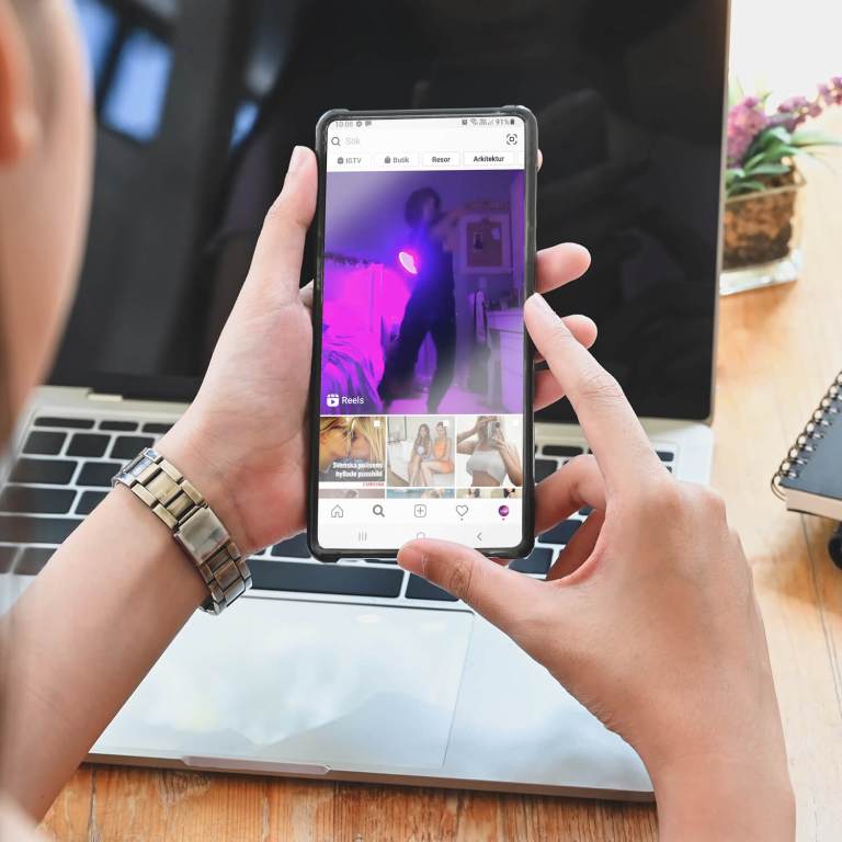 Videoannonser Instagram - hand håller telefon framför datorskärm