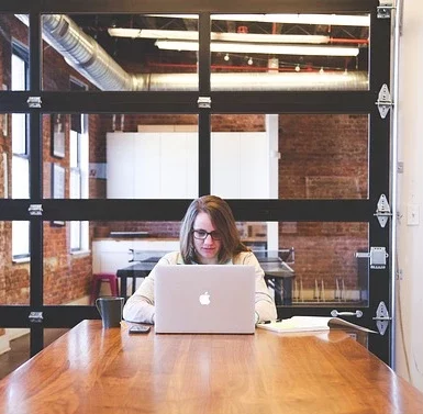 Nybörjarguide SEO visar kvinna som sitter framför laptop vid ett stort skrivbord