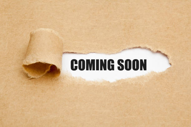 The phrase Coming Soon appearing behind ripped brown paper. Concept about upcoming promising event approaching in near future.