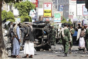 Armed Houthis gather around the wreckage of a vehicle set a blaze by angry protesters after Houthis fired on them in Yemen's central town of Ibb