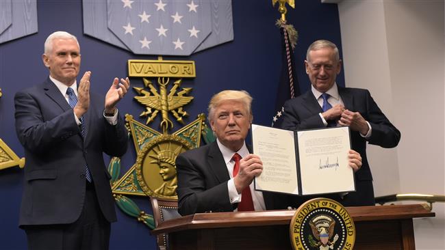 US President Donald Trump shows his signature on executive orders alongside US Defense Secretary James Mattis (R) and US Vice President Mike Pence on January 27, 2016 at the Pentagon in Washington, DC. (Photo by AFP)