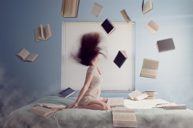 vrouw op bed met rondvliegende boeken. stress leidt tot niet meer kunnen nadenken. te veel aan je hoofd hebben