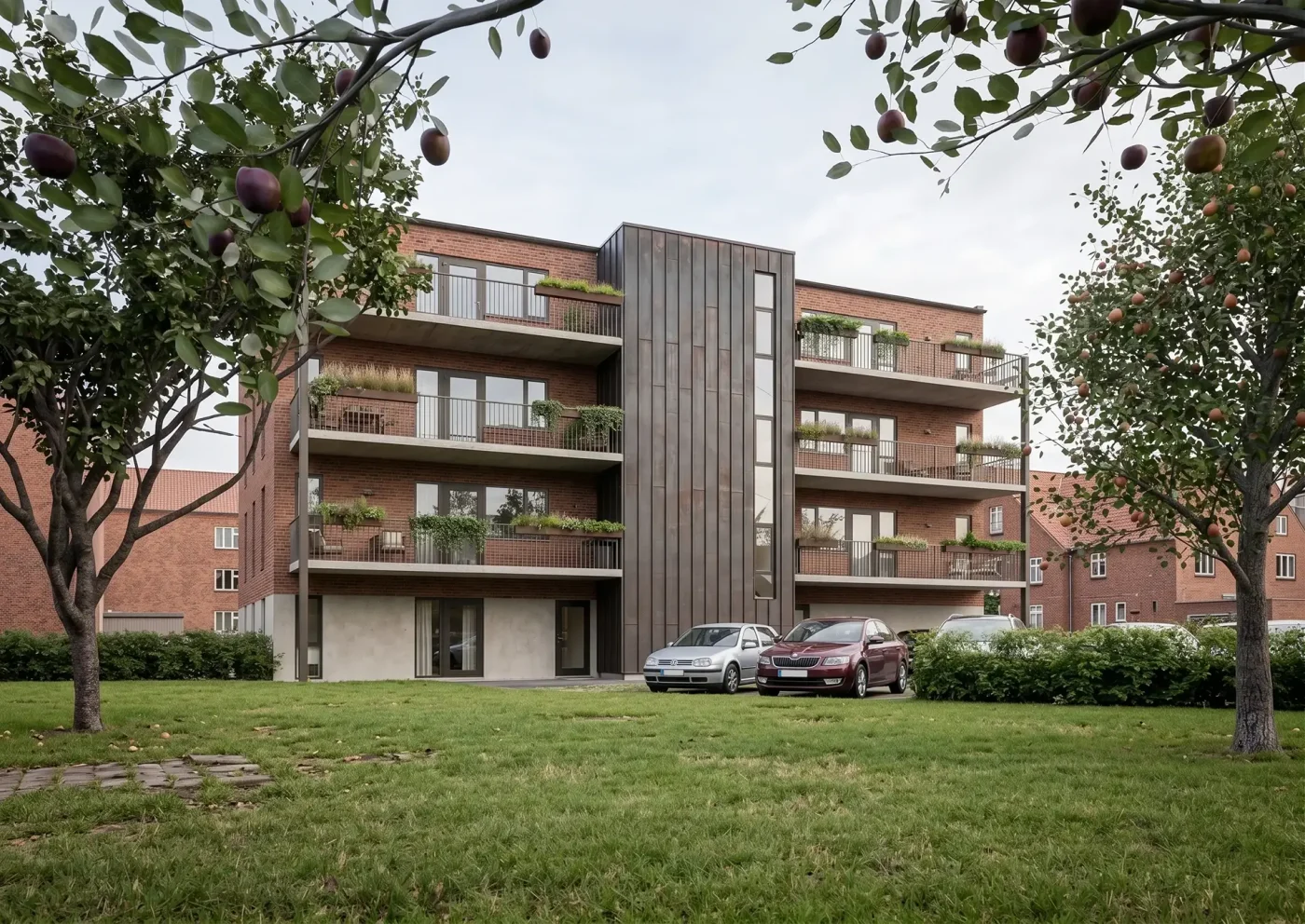 Grøn gårdhave ved Købmandsgården i Skørping med udsigt til lejlighedsbygning og fælles udearealer.
